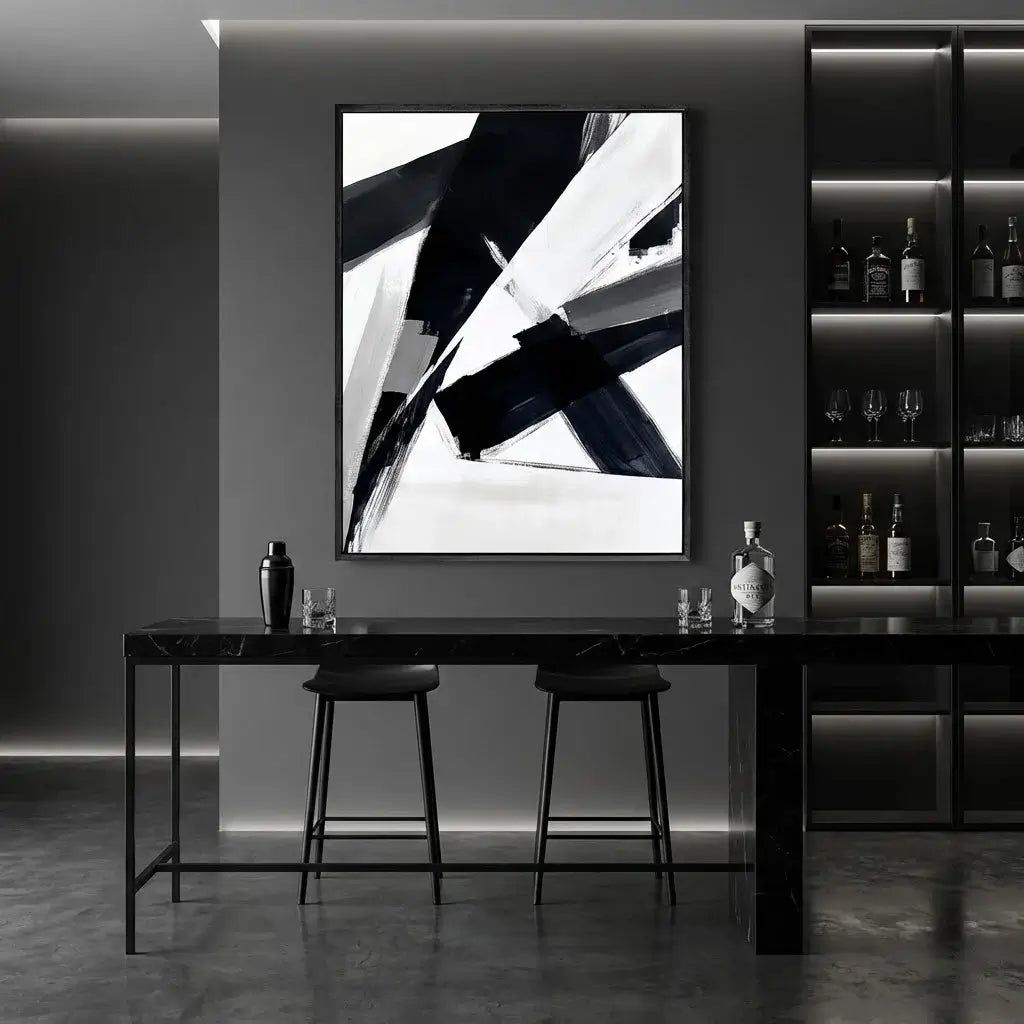 Modern interior with a black and white abstract painting on a gray wall, a black dining table, and bar shelves with bottles.