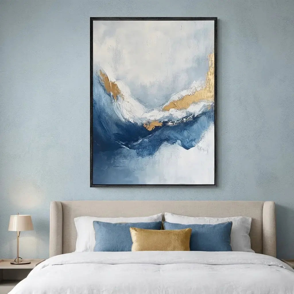 Abstract art piece with blue and gold tones on a wall above a bed.