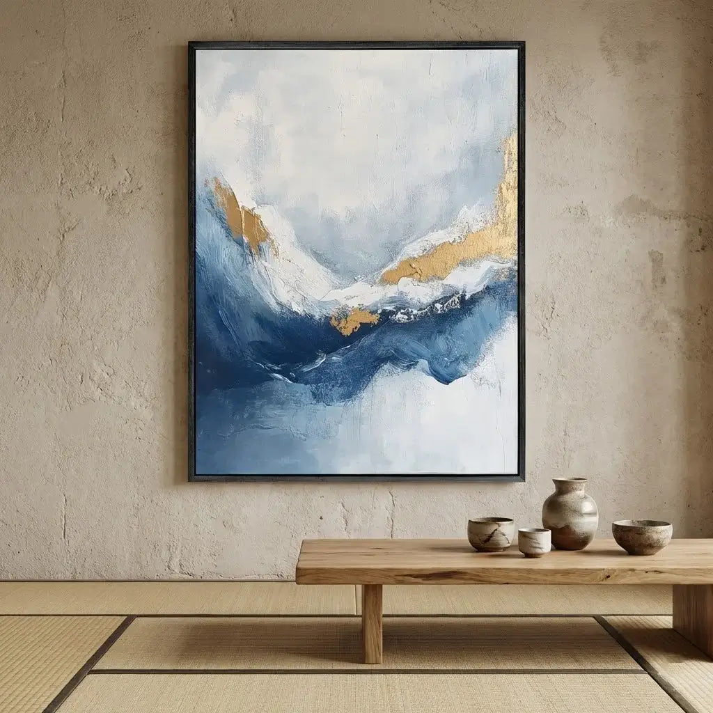 Abstract painting with blue and gold tones on a beige wall above a wooden table.