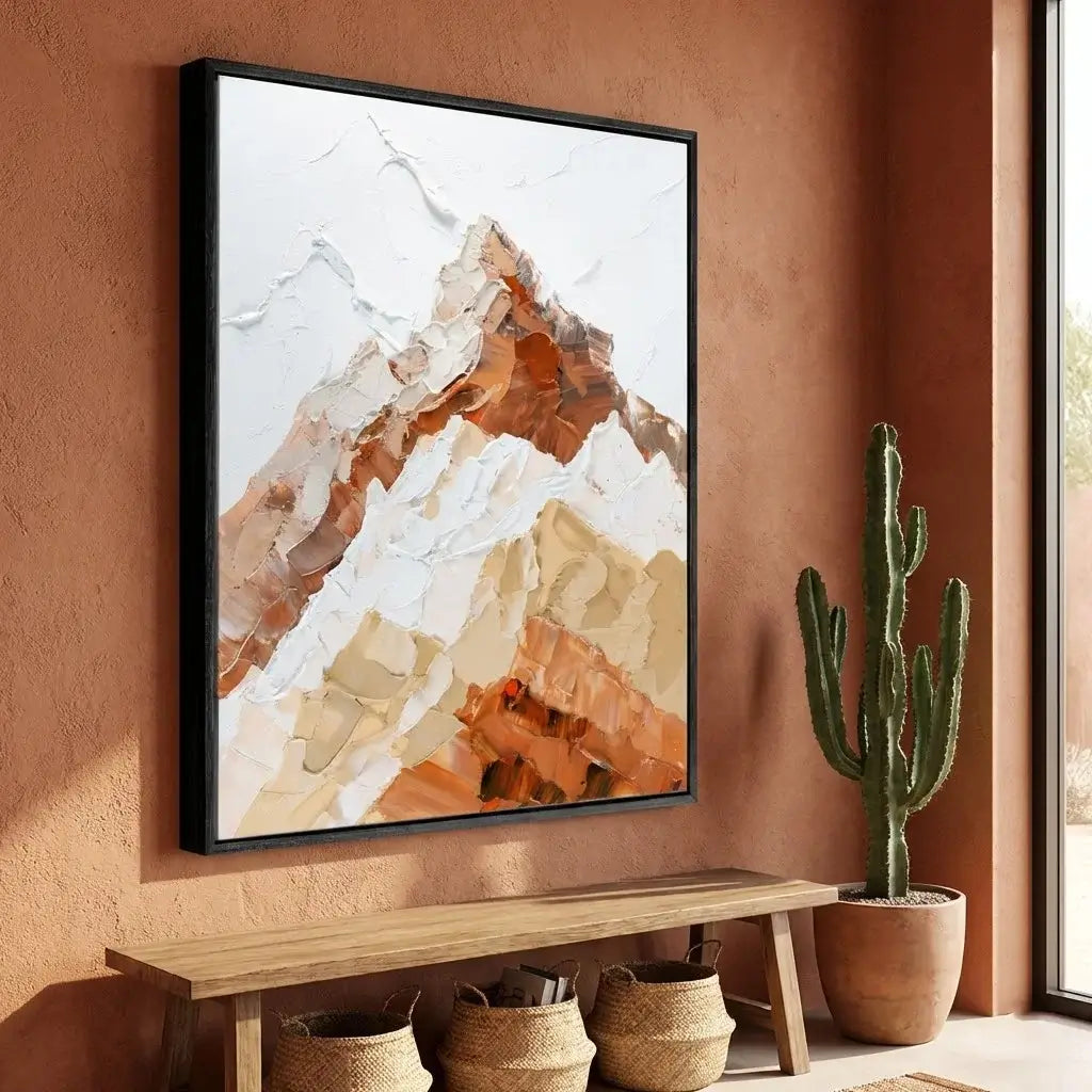 Abstract mountain painting on a wall with a cactus and wooden bench below.