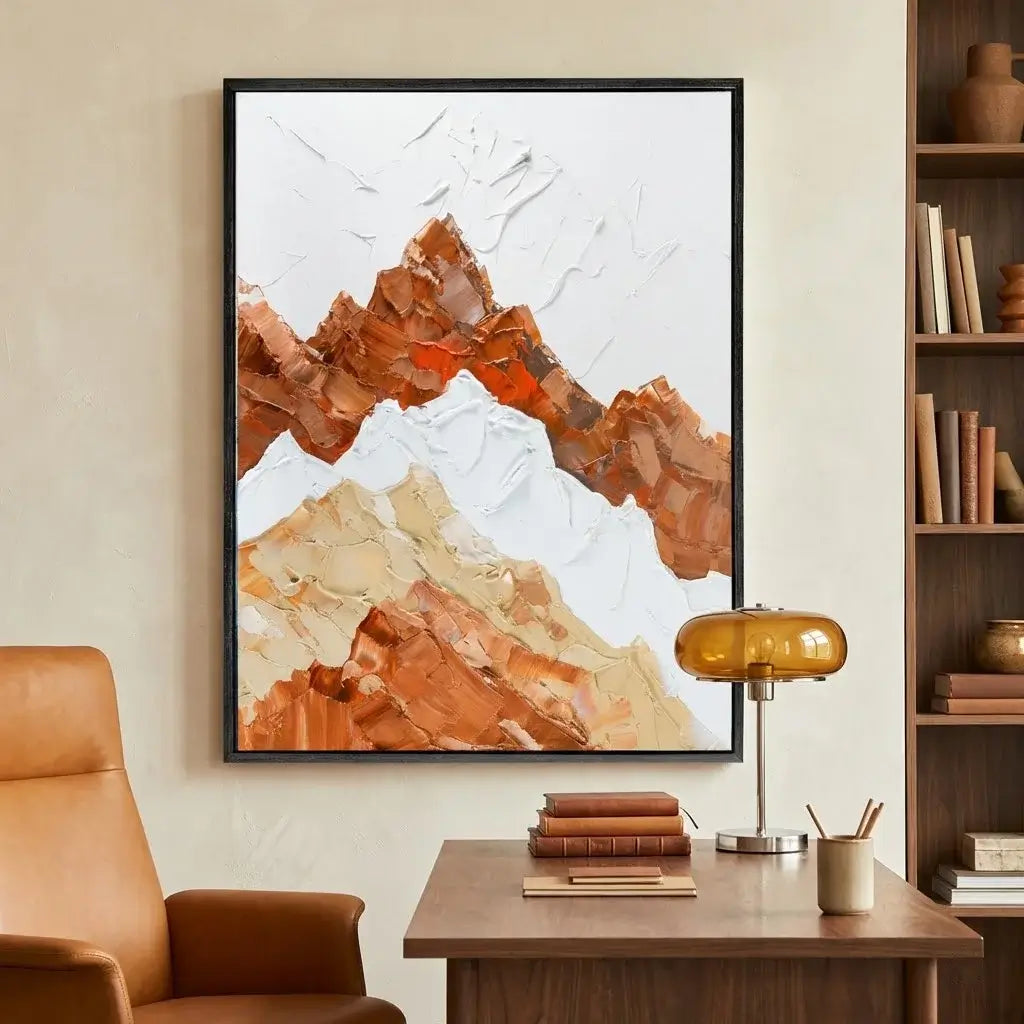 Framed abstract mountain art piece on a wall above a desk with books and decor.