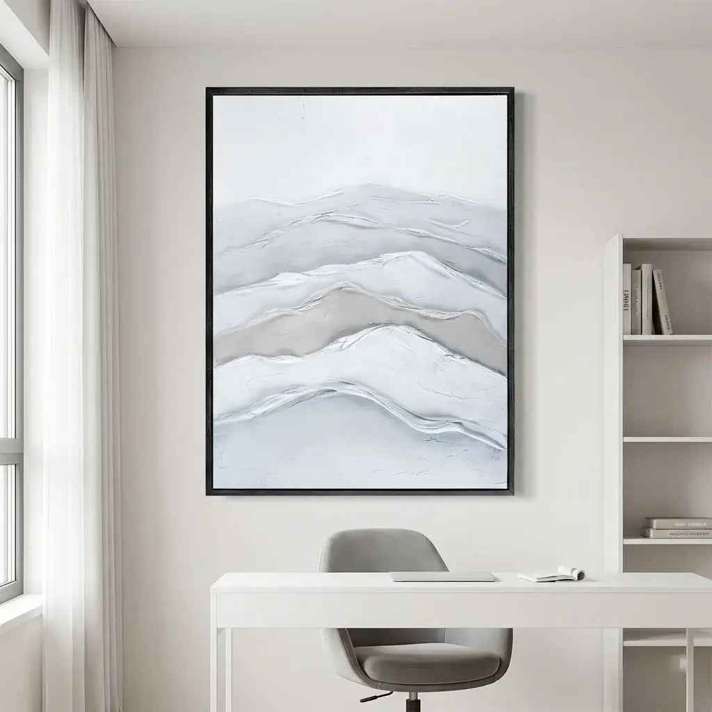 Framed abstract mountain artwork above a desk in a modern office setting.