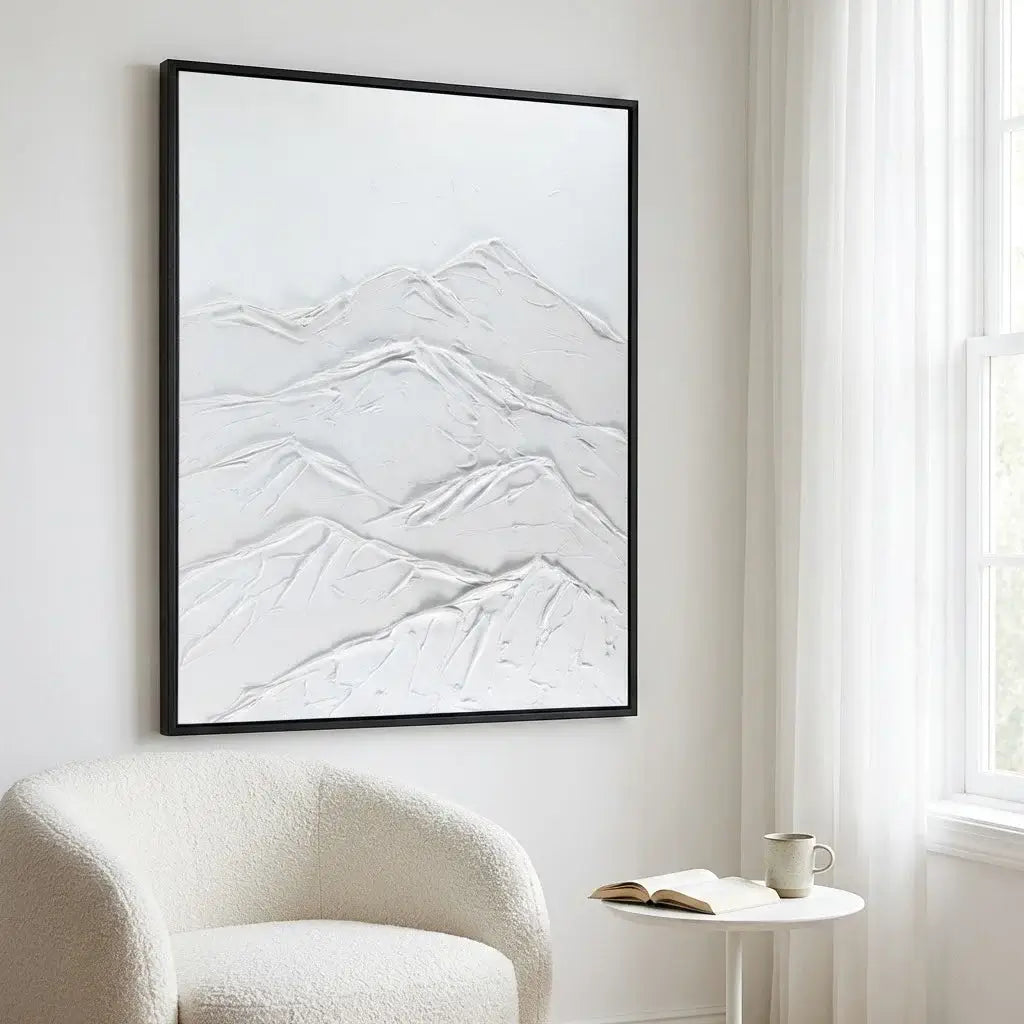 Framed abstract art piece on a wall above a white armchair with a side table.
