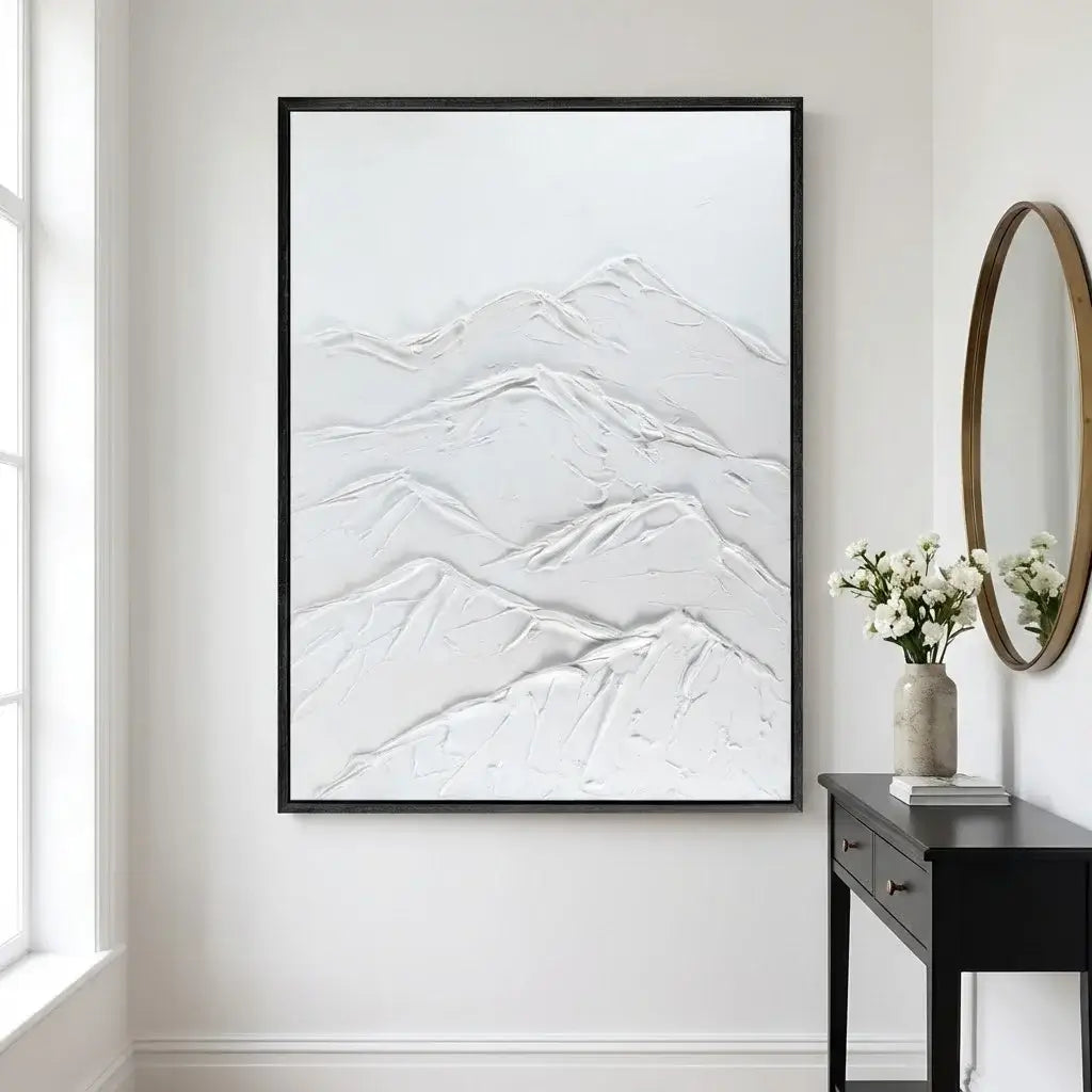 Framed abstract artwork on a wall with a vase of flowers and mirror on a side table.