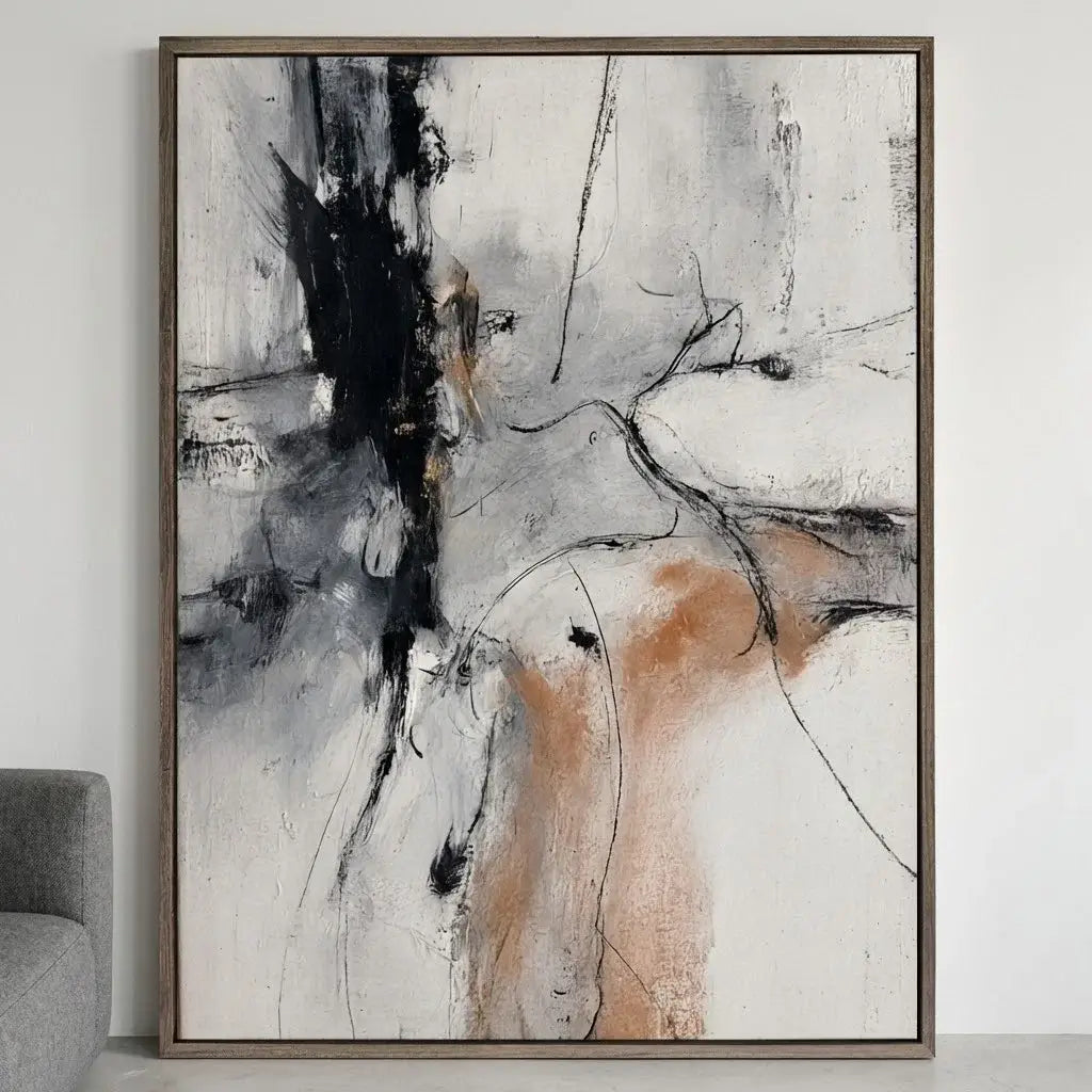Abstract art painting with black, white, and brown colors in a wooden frame on a wall.