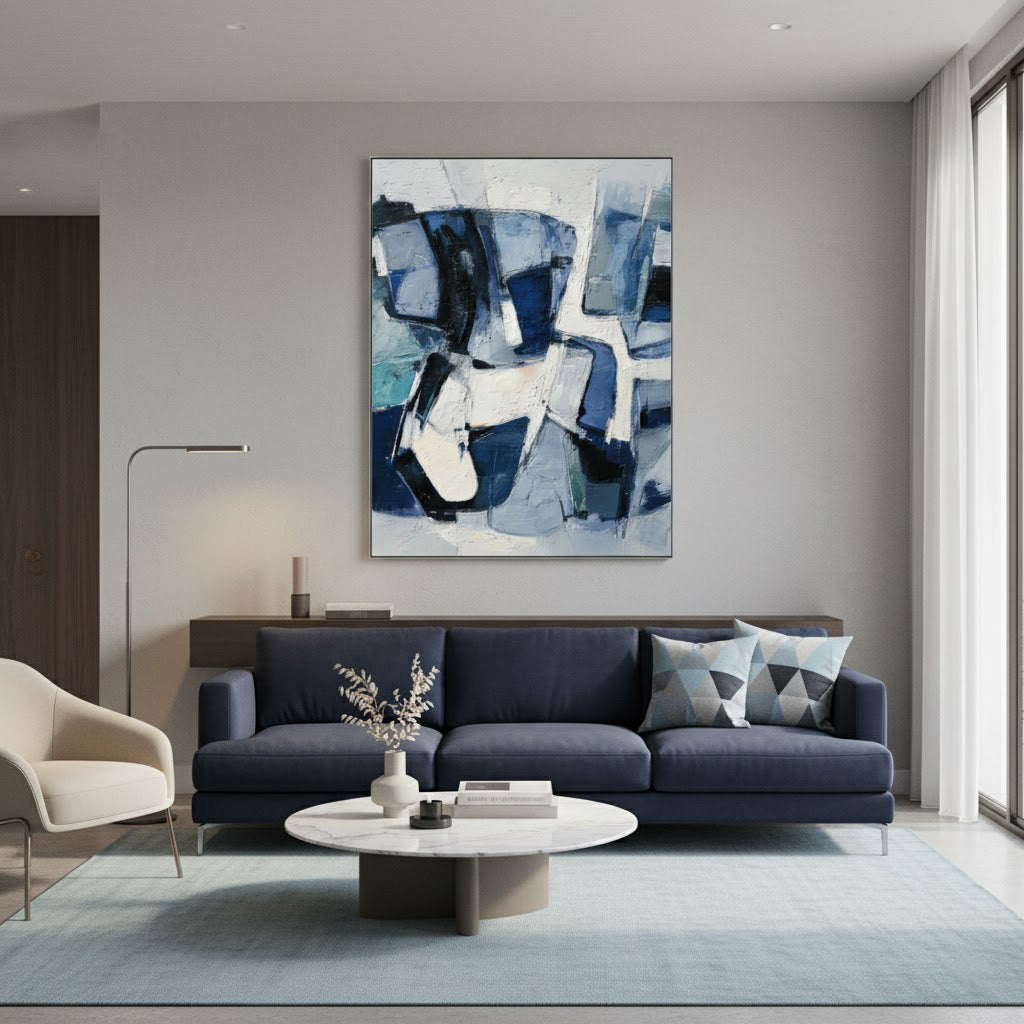 Modern living room with a blue abstract painting on the wall, dark gray sofa, and white coffee table.