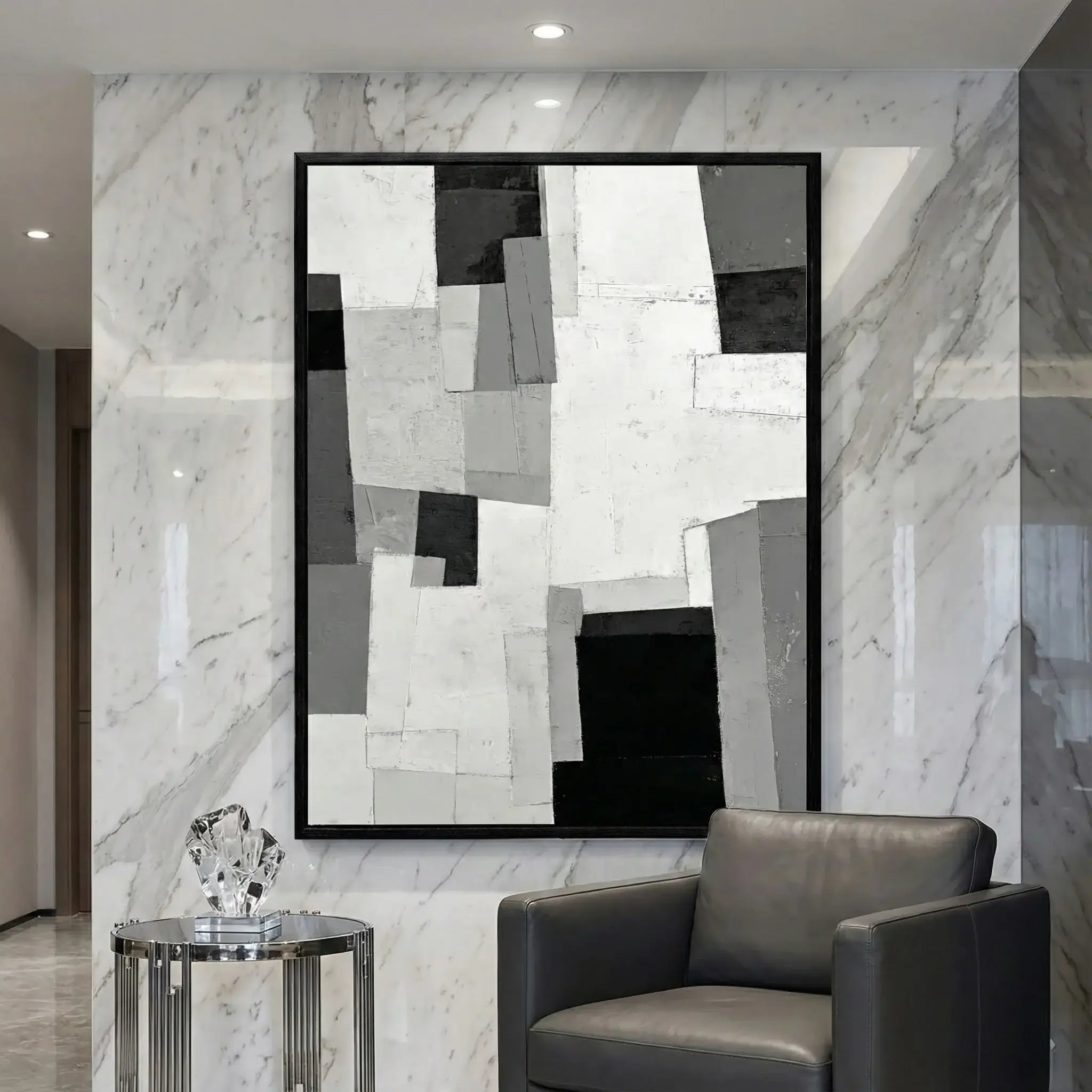 Abstract art piece on a marble wall with a modern chair and side table.