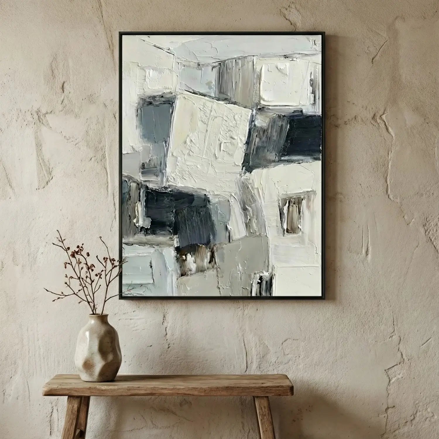 Abstract art piece on a textured wall above a wooden table with a vase.