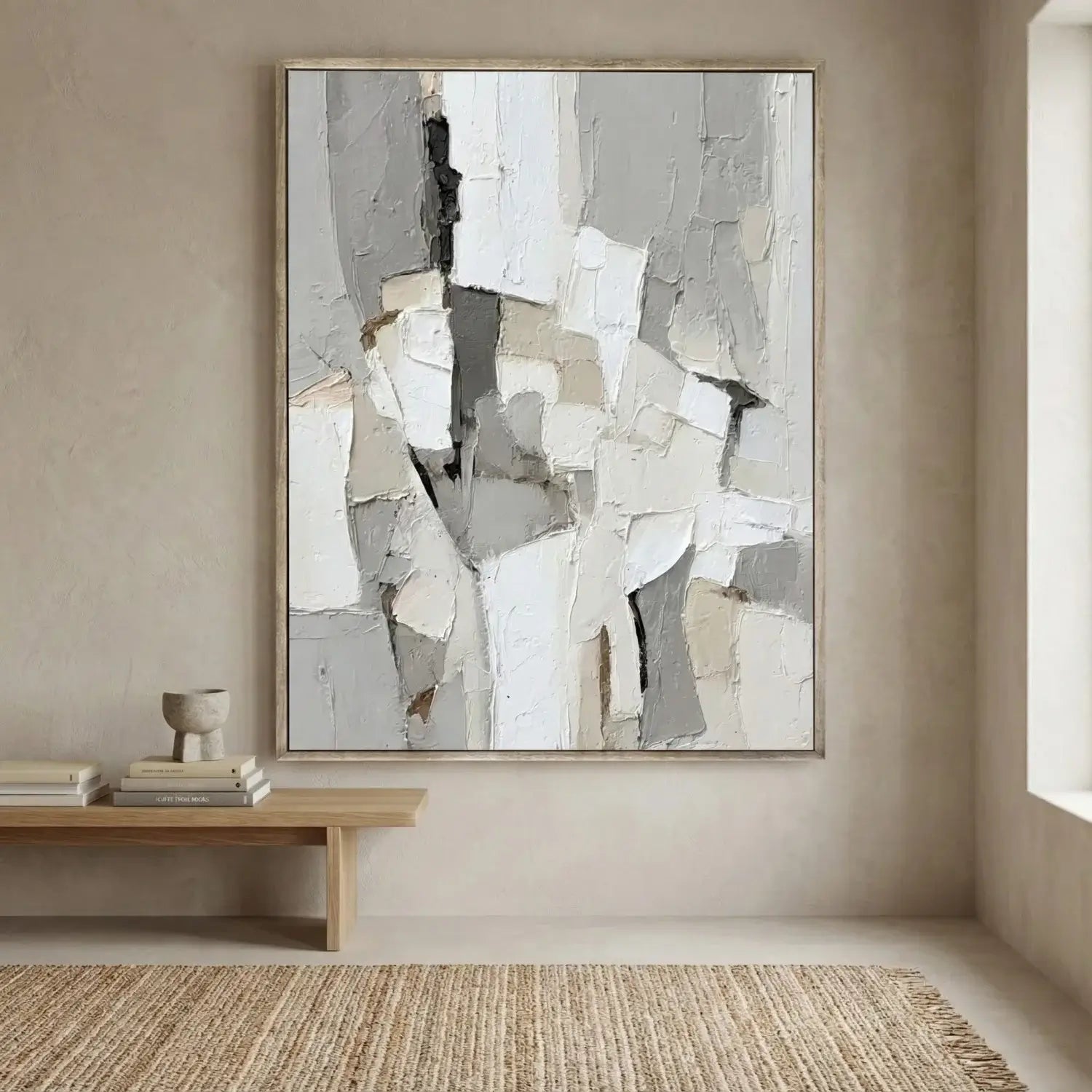 Abstract art piece in a neutral-colored room with a wooden bench and books.
