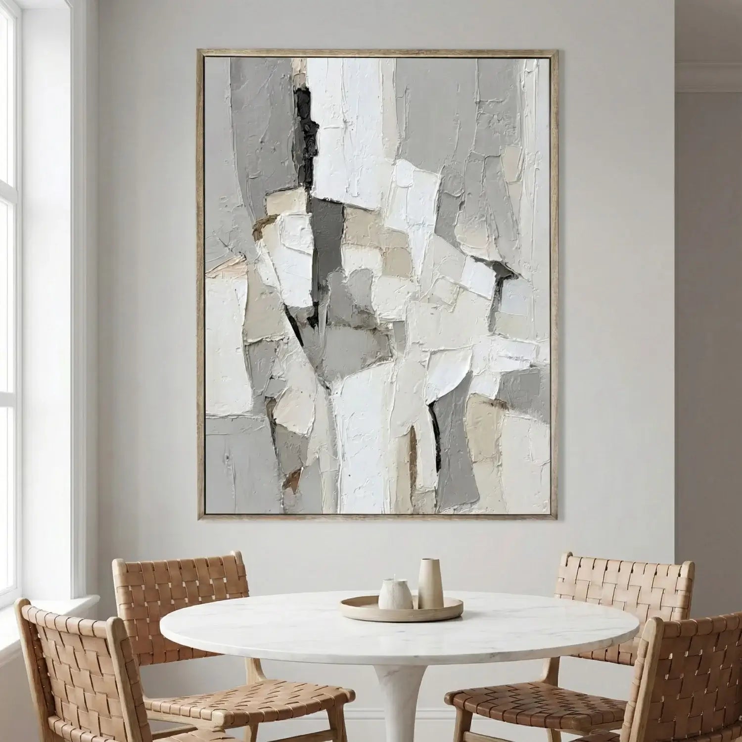 Abstract art piece on a wall above a dining table with chairs.