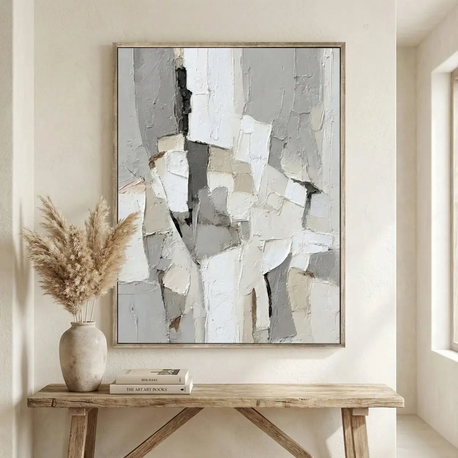 Abstract art piece on a wall above a wooden console table with decor items.