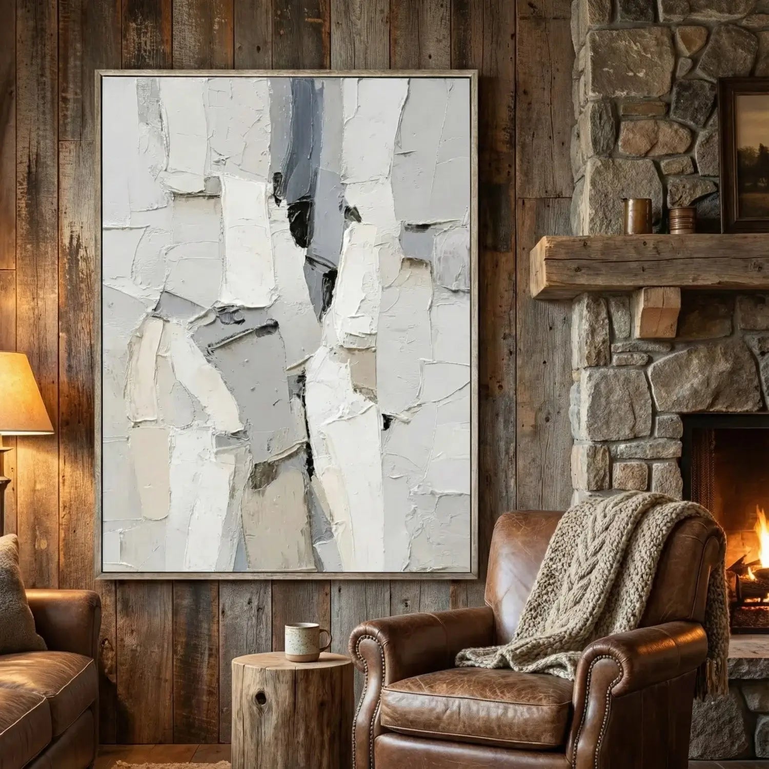 Living room with abstract art, leather armchair, and stone fireplace.