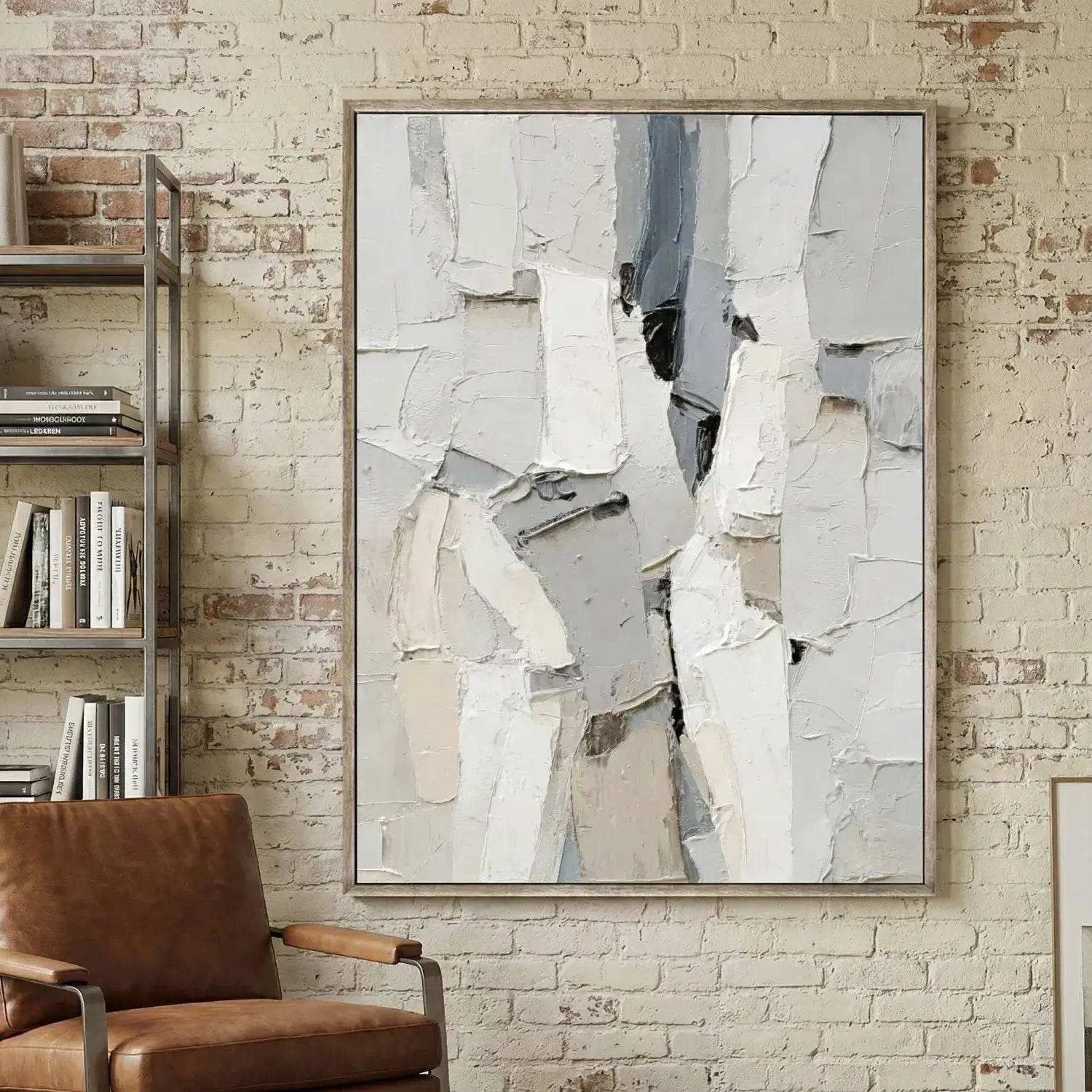 Abstract art piece on a brick wall with a brown chair and bookshelf.
