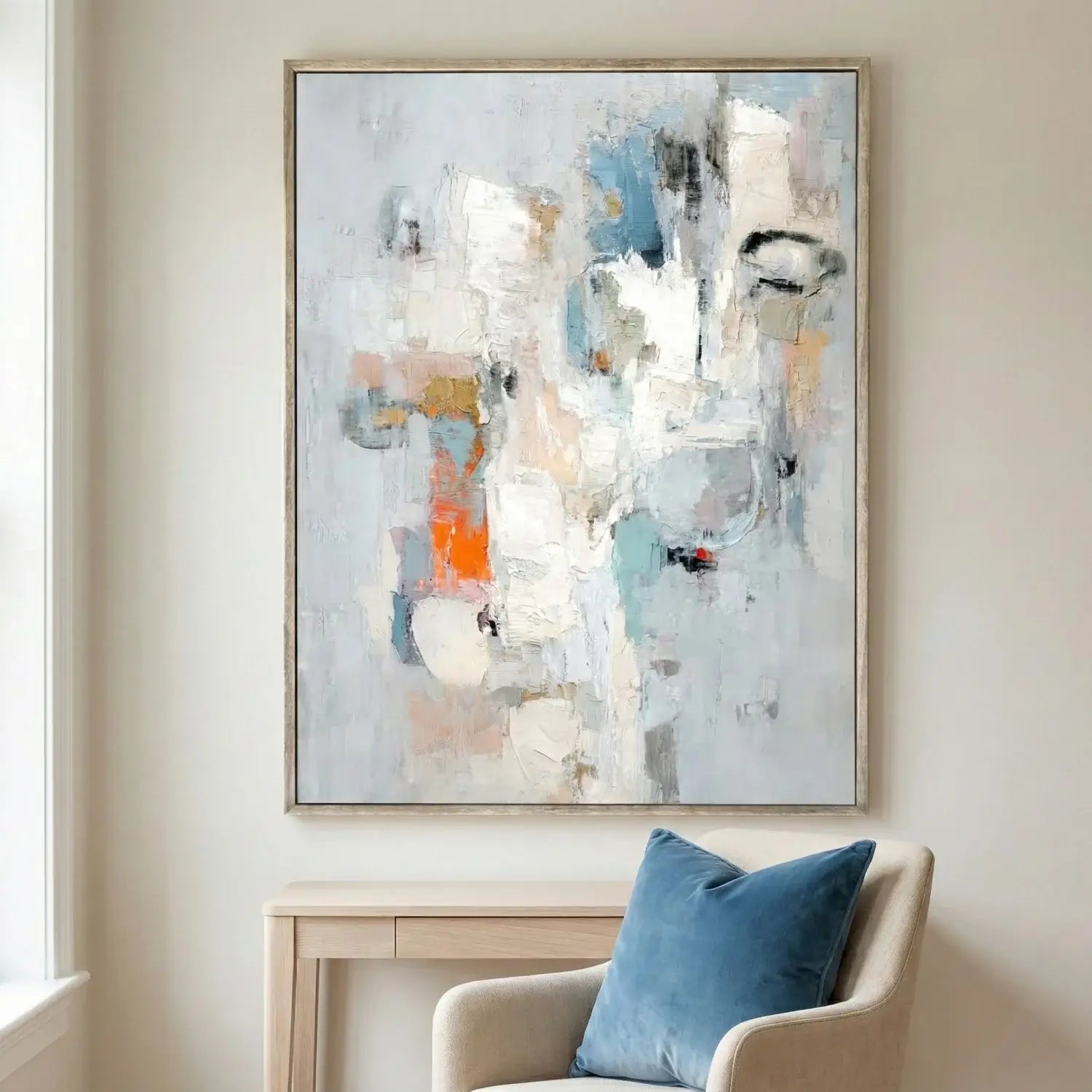Abstract painting on a wall above a chair with a blue pillow
