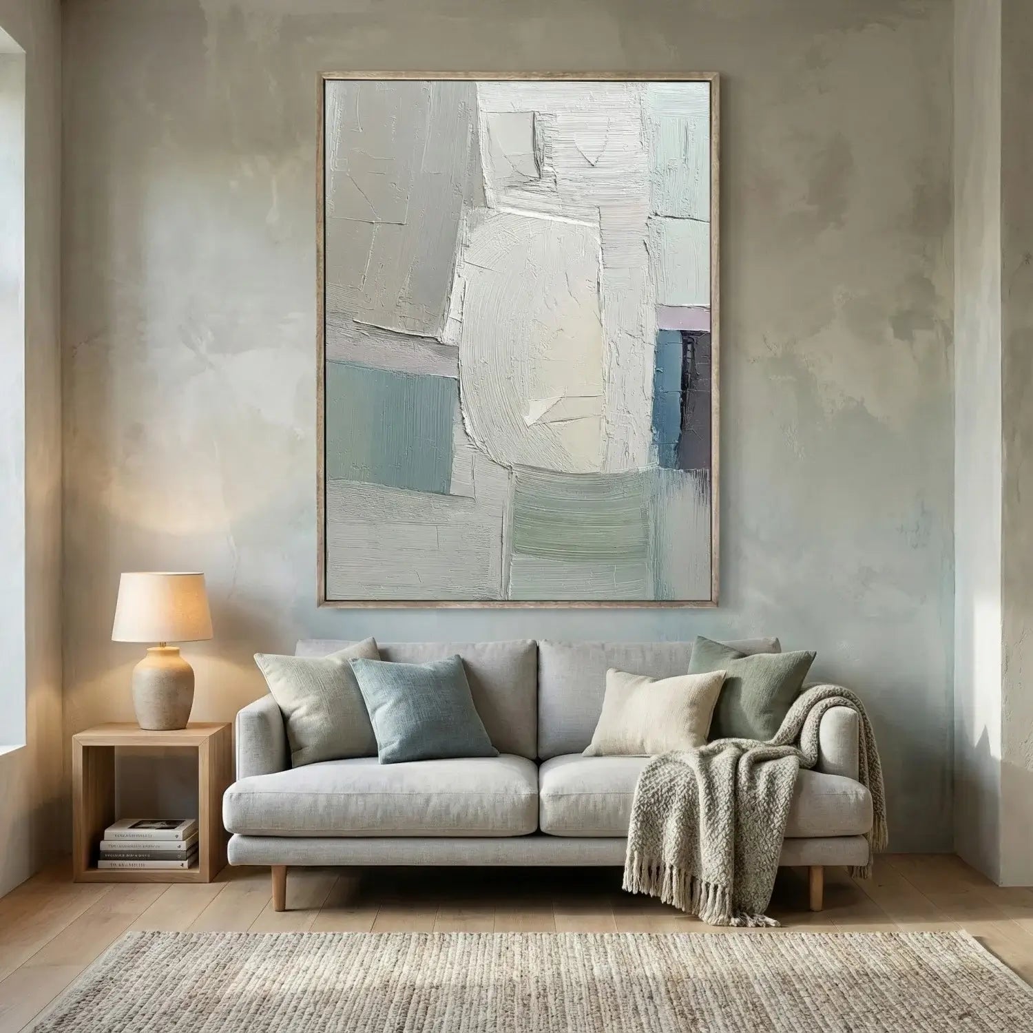 Living room with a gray sofa, abstract painting, and side table with lamp.