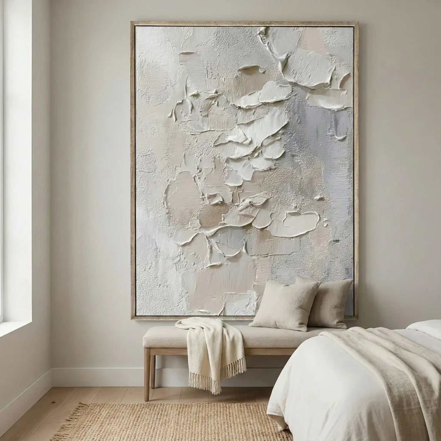Abstract painting in a neutral-colored bedroom with a bench and pillows.