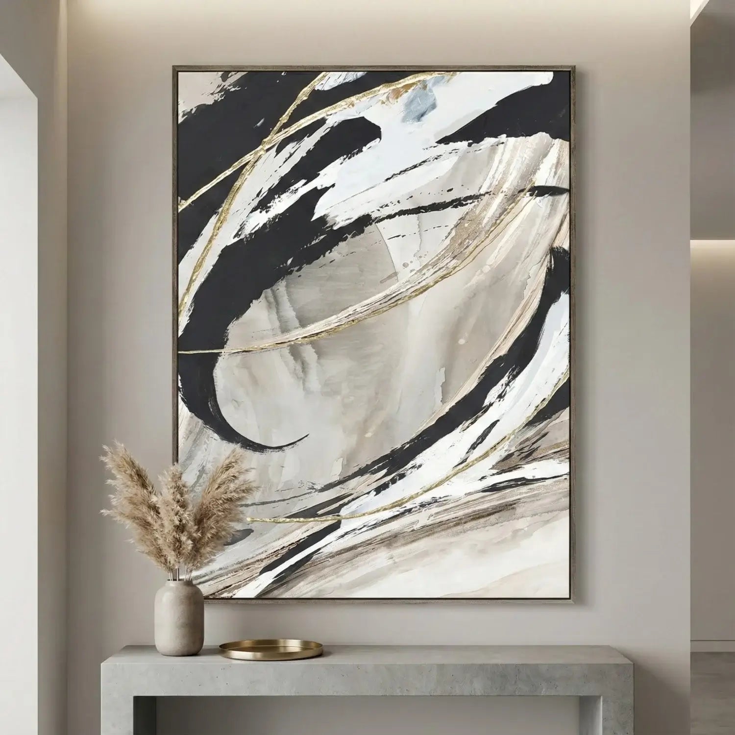 Abstract art piece with black, white, and gold brush strokes on a wall above a console table.