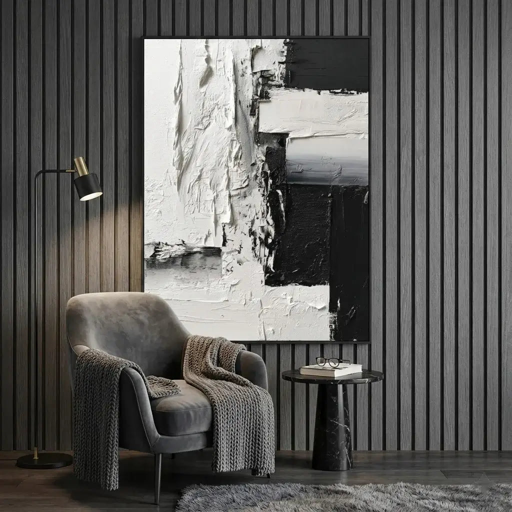 Gray armchair with a textured blanket in front of a large abstract painting on a striped wall.
