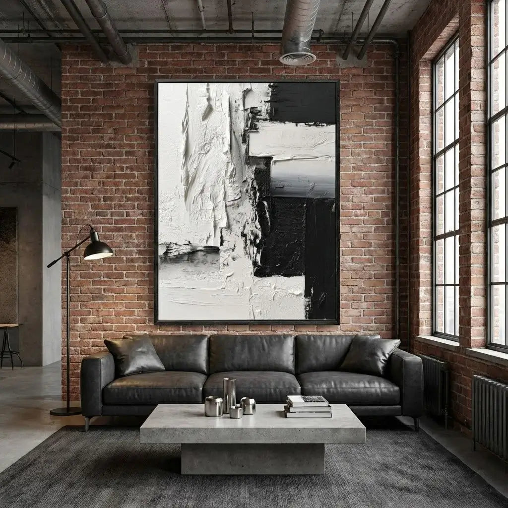 Modern living room with a black leather sofa, abstract art on brick wall, and large windows.