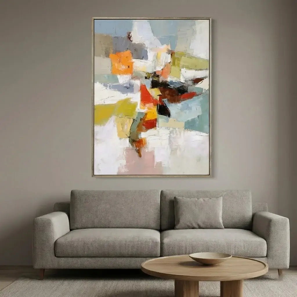 Gray sofa in a living room with a colorful abstract painting above it.