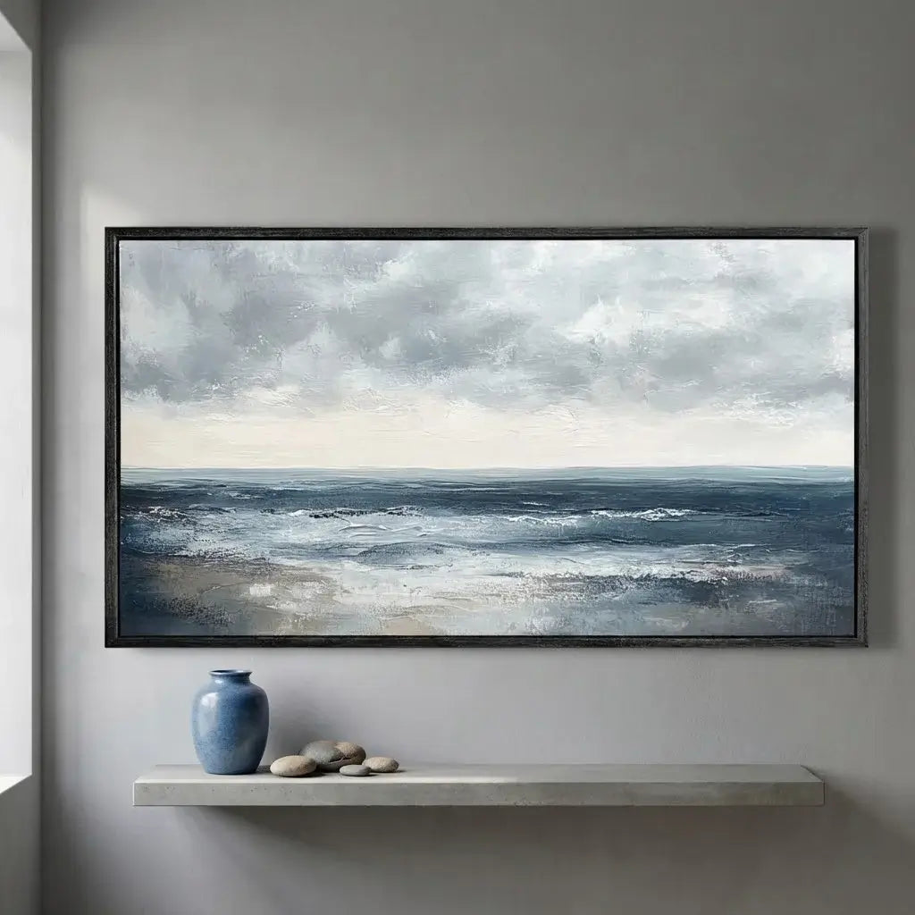 Framed artwork of a seascape with clouds on a wall above a shelf with decorative items.