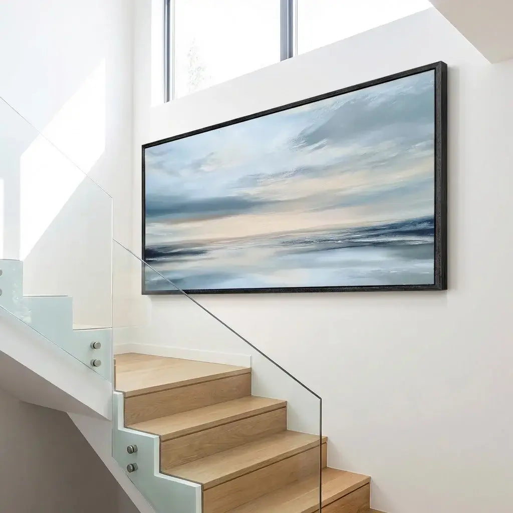Modern staircase with a framed artwork of a beach scene on the wall.