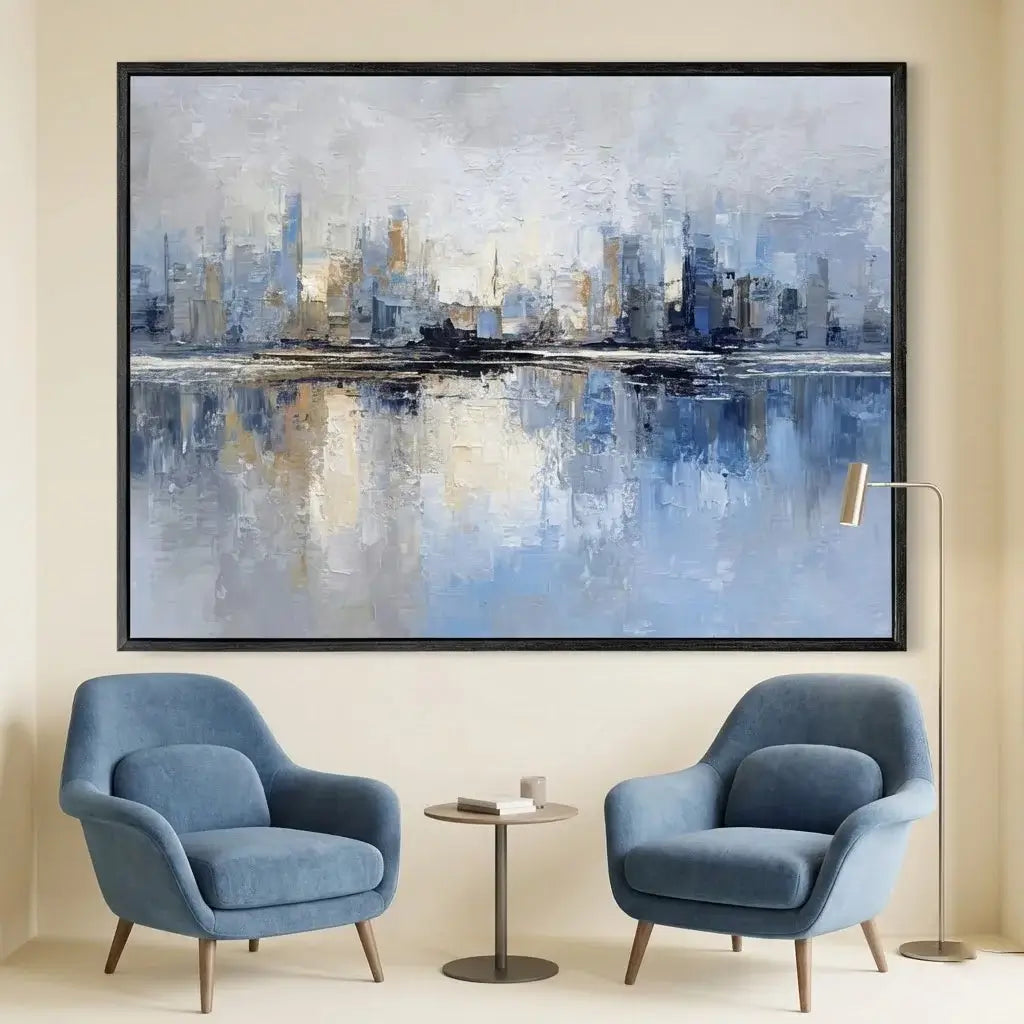 Abstract cityscape painting on a wall above two blue armchairs in a room.