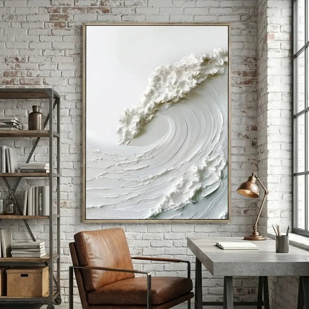 Framed abstract artwork on a brick wall above a desk with a chair.