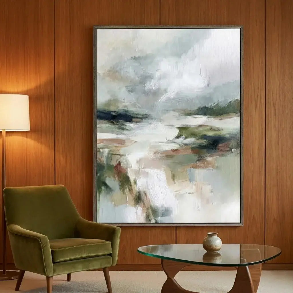Abstract landscape painting on a wooden wall above a green armchair and glass table.