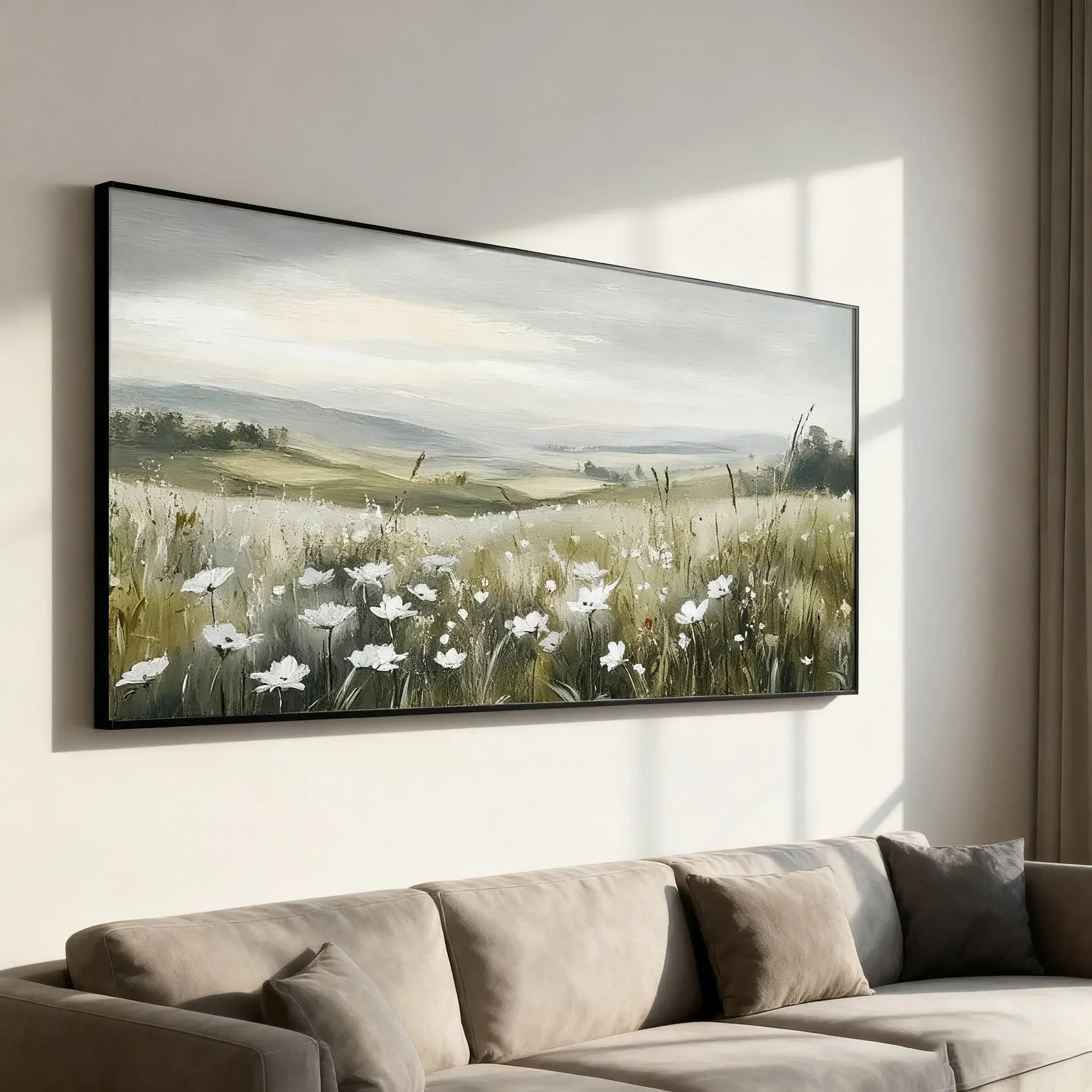 Framed artwork of a landscape with flowers on a wall above a sofa.