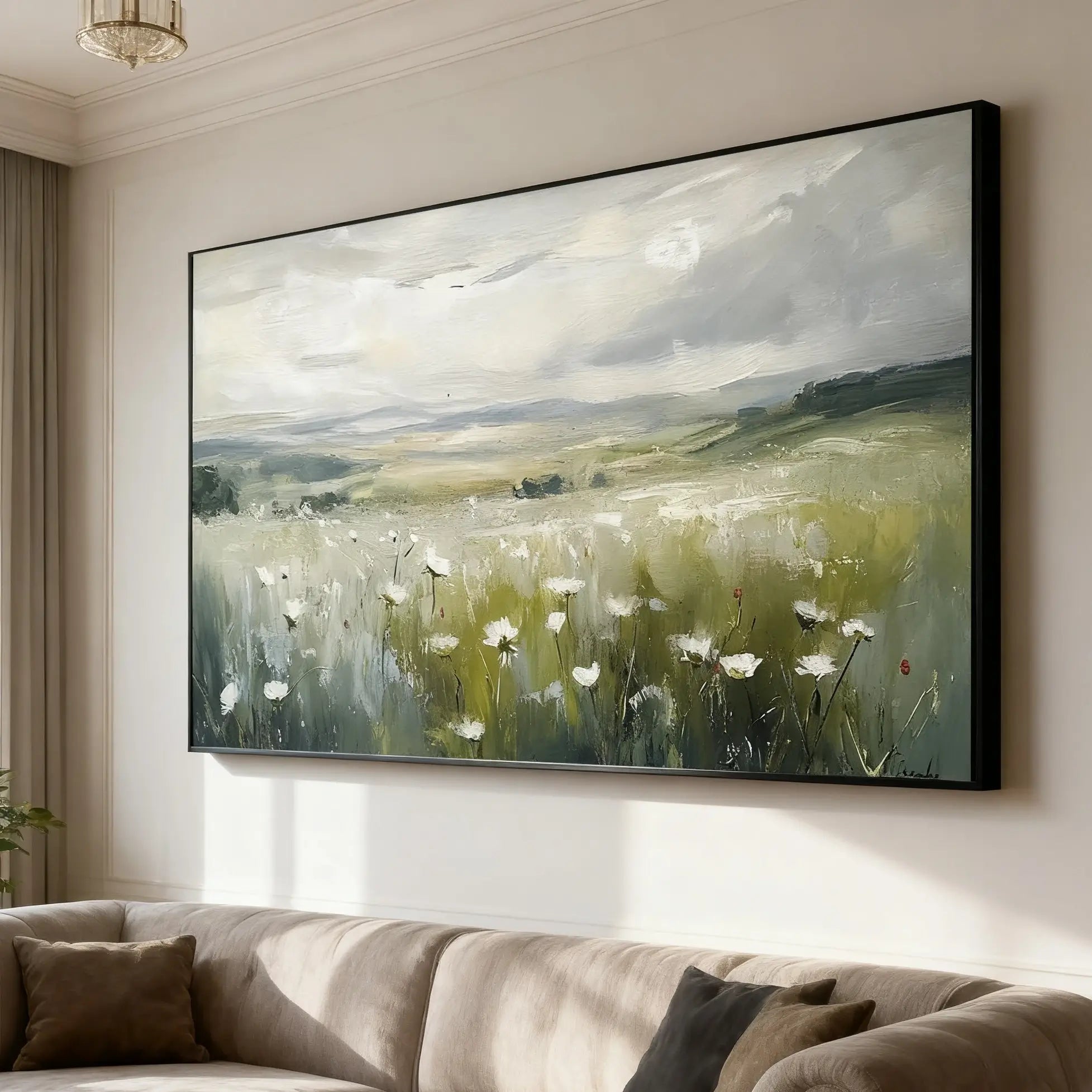 Large painting of a landscape with fields and clouds above a beige sofa.
