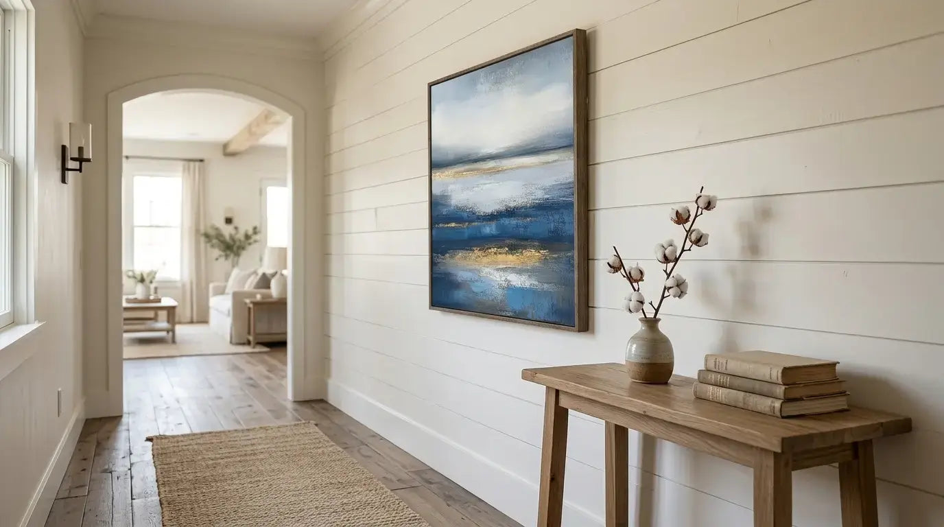 Narrow hallway with a wooden bench, vase, and books against a wall with a large abstract painting.