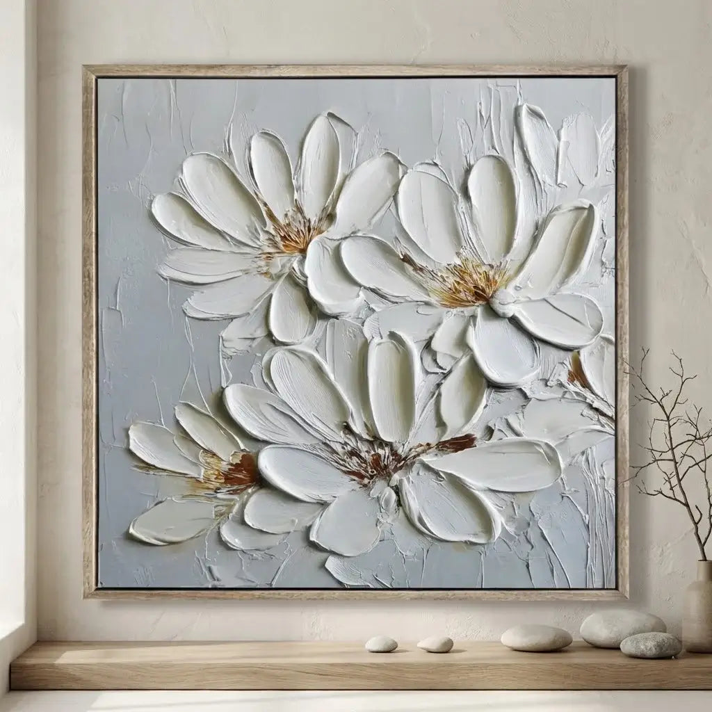 Framed abstract floral artwork on a wall with decorative stones below.