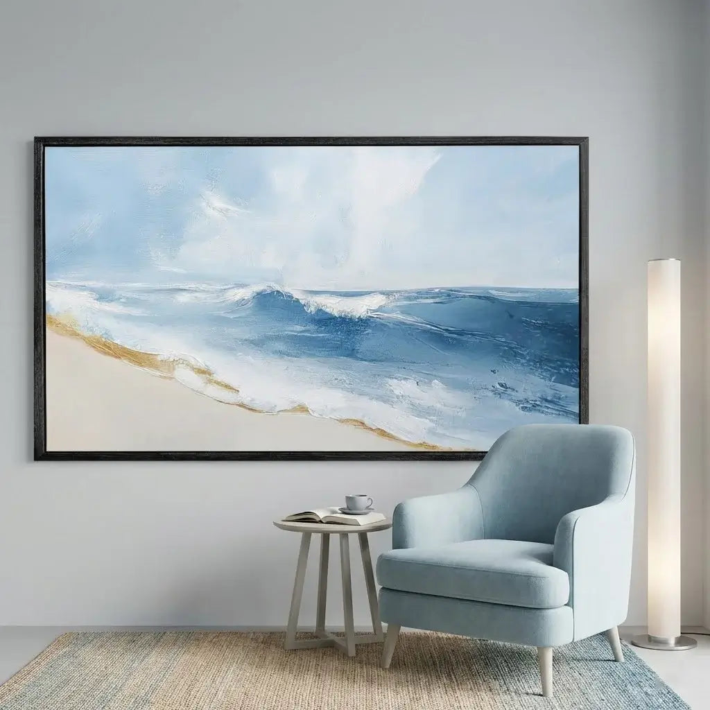 Living room with a large framed beach scene on the wall, a light blue armchair, and a small round table.