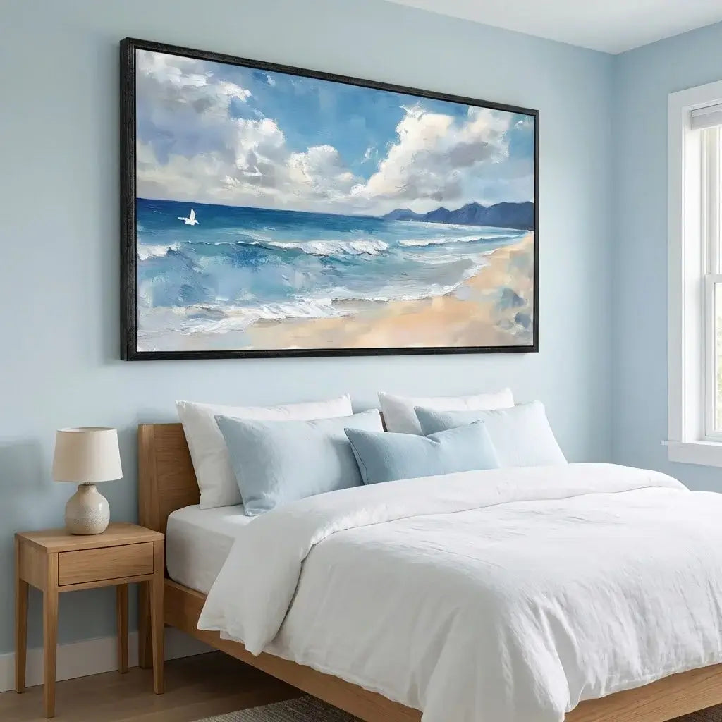 Bedroom with a large framed beach scene painting on the wall above a bed.