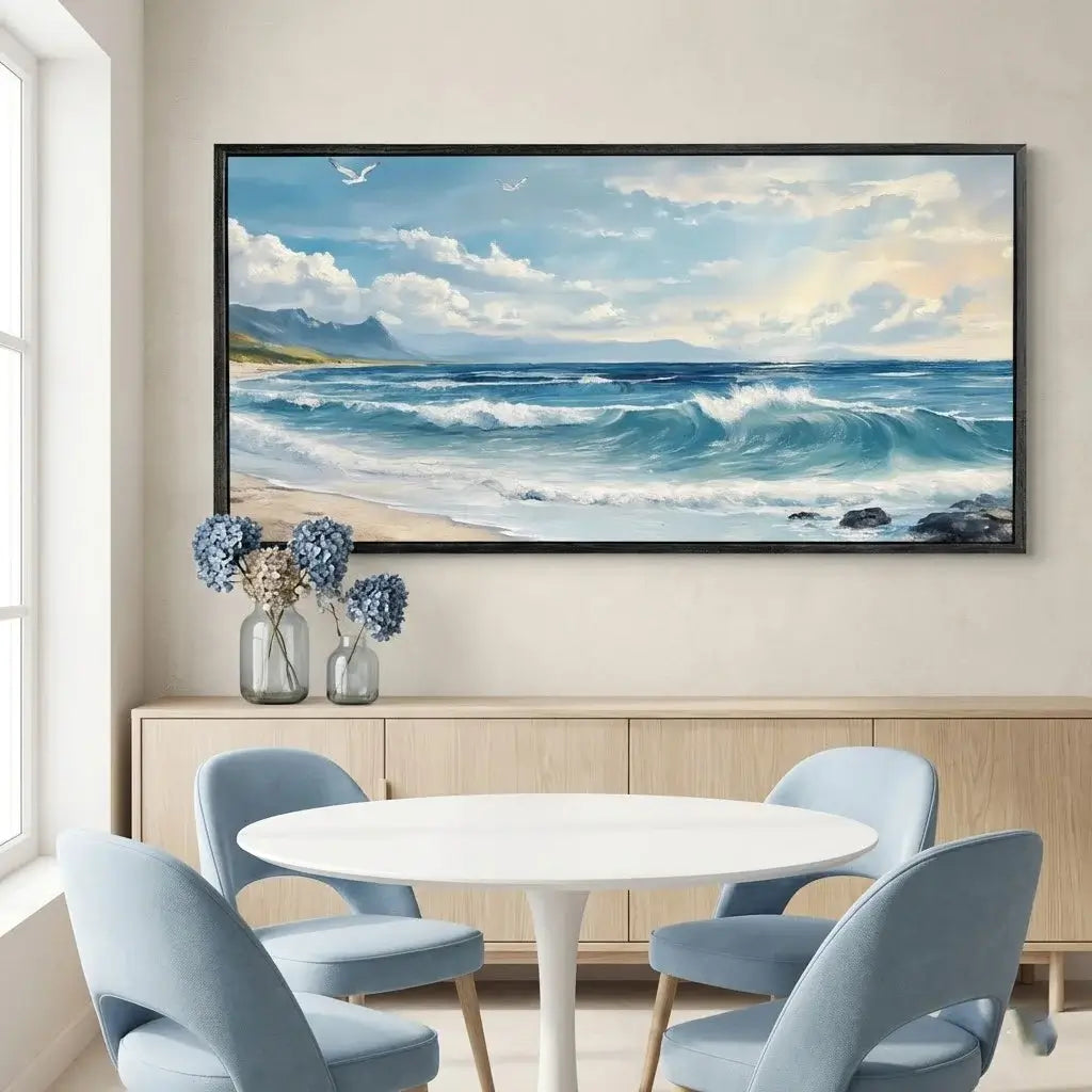 Framed beach scene painting above a dining table with chairs.