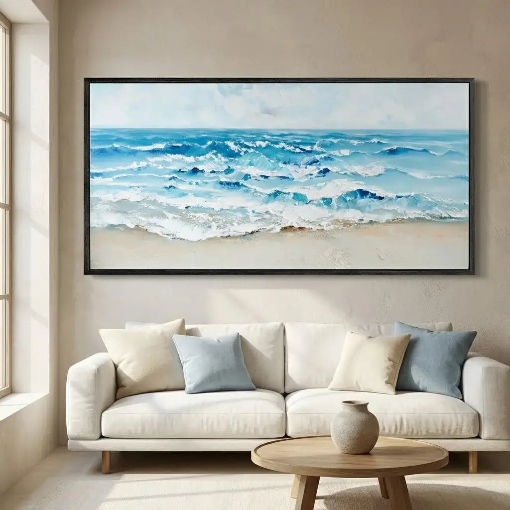Framed beach scene painting above a beige sofa with decorative pillows in a living room.