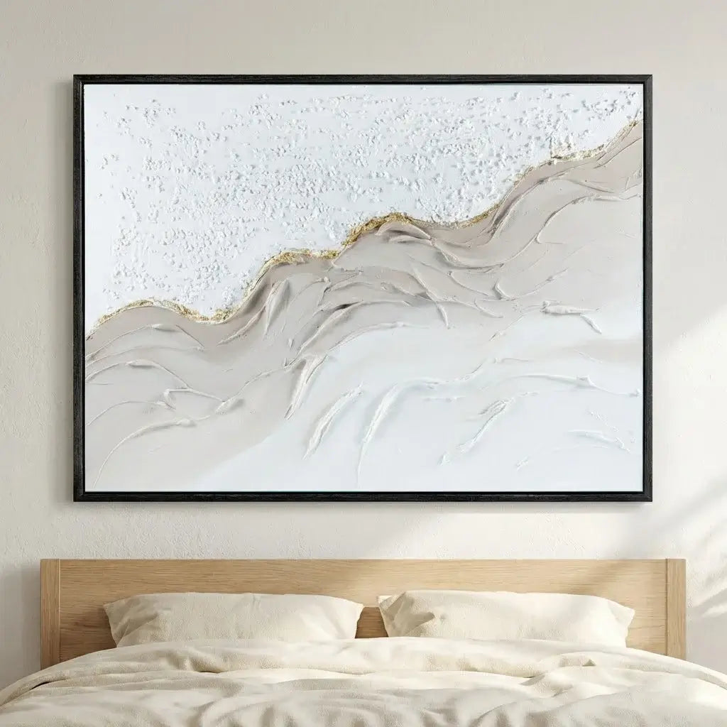 Abstract wall art in a black frame above a bed with neutral tones.