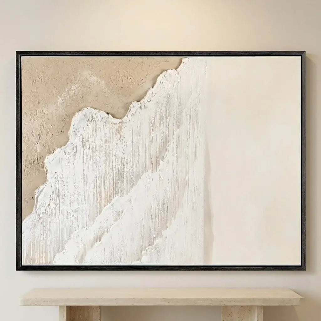 Abstract art piece with white and beige tones in a black frame on a wall.