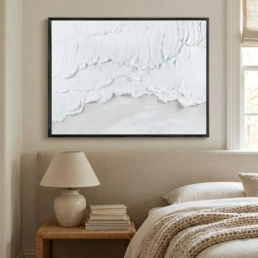 Modern bedroom with abstract wall art, lamp, and books on a nightstand.