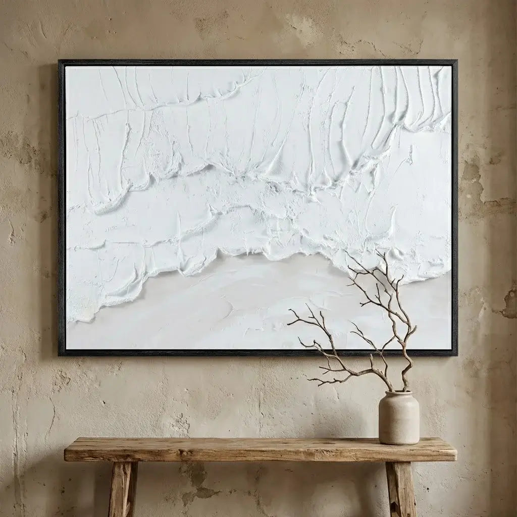 Abstract white painting on a beige wall above a wooden console table with a vase and branches.