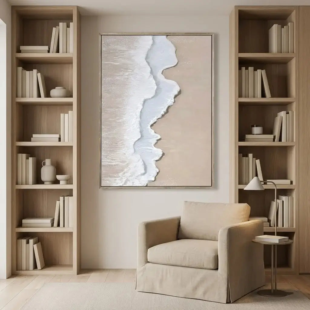 Modern living room with beige armchair, bookshelves, and abstract wall art.