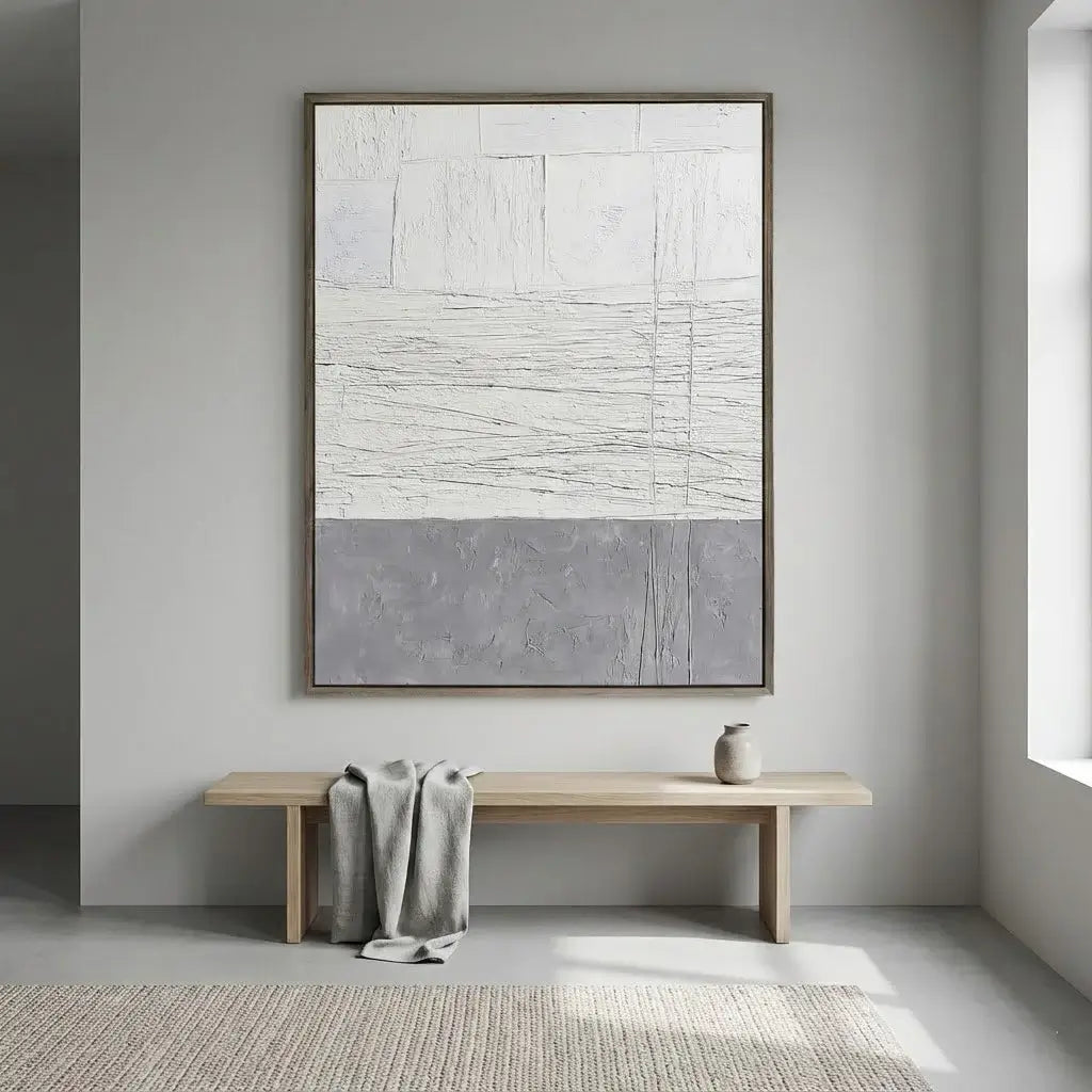 Abstract painting on a wall above a wooden bench with a towel draped over it in a minimalistic room.