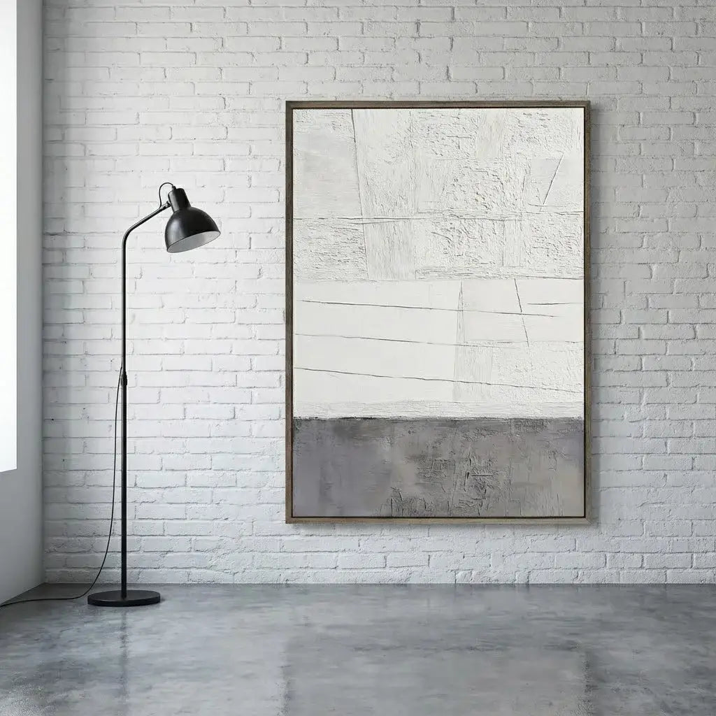 Abstract art piece on a white brick wall with a floor lamp.
