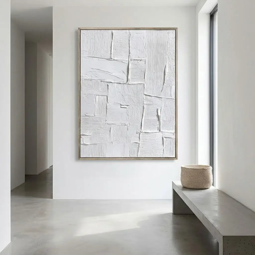 Abstract artwork on a white wall in a minimalistic room with a bench and basket.