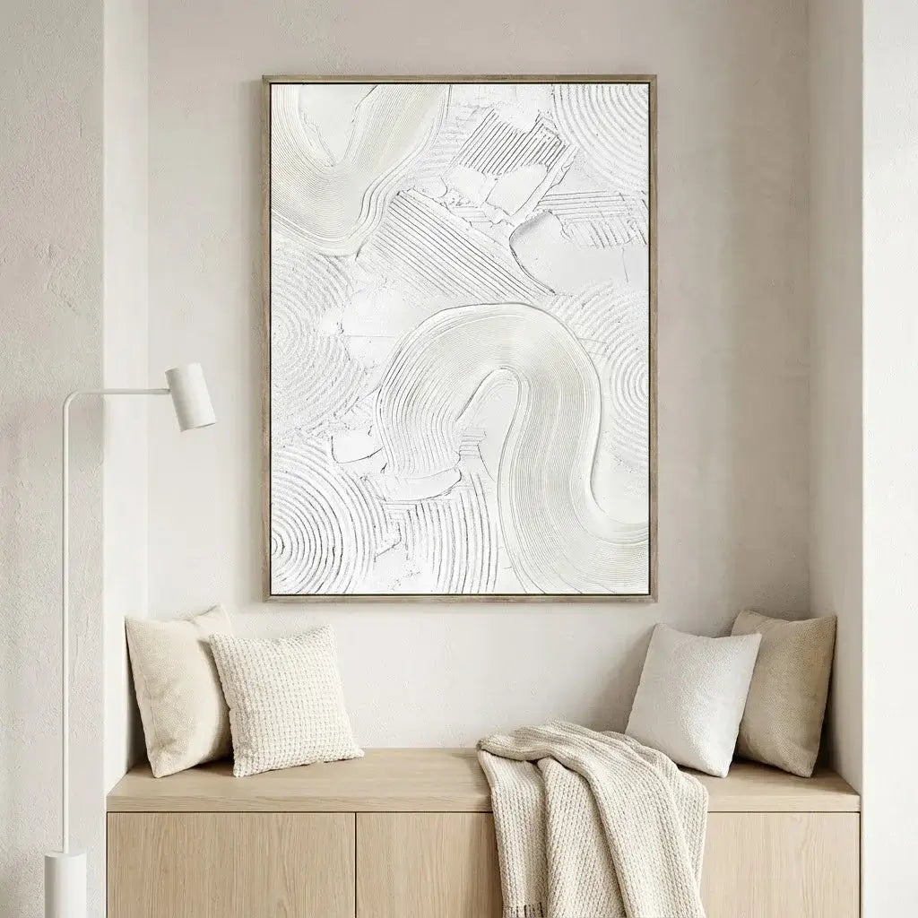 Abstract artwork on a wall above a wooden bench with cushions and a blanket.