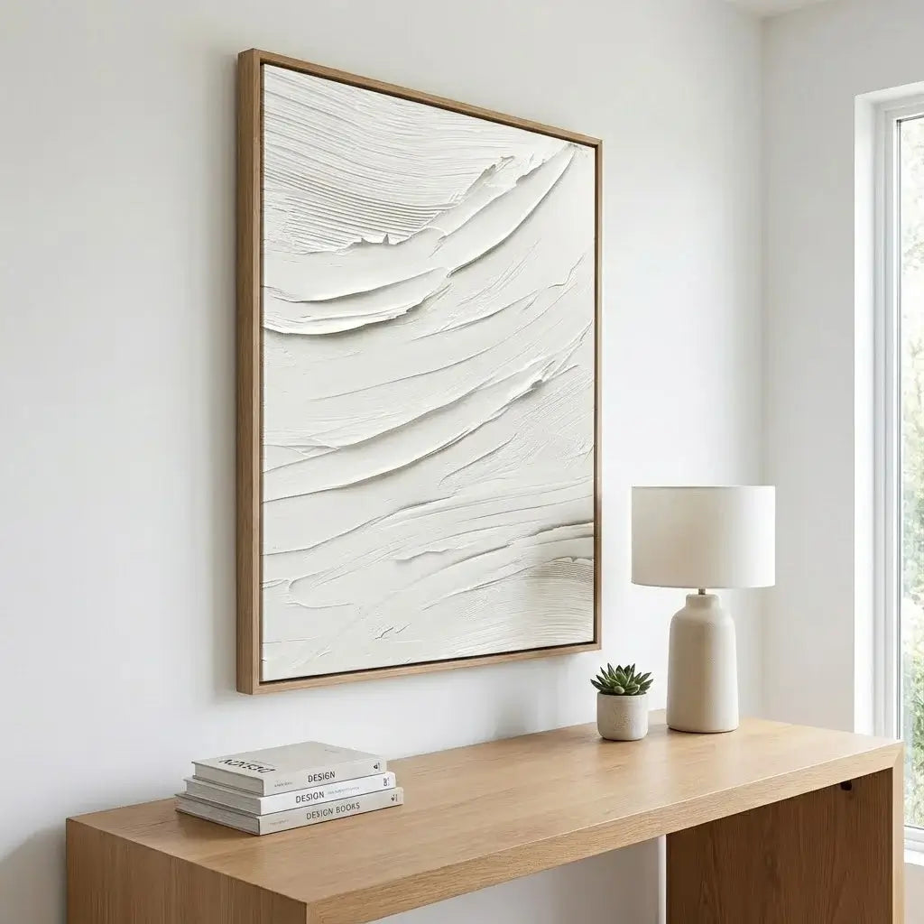 Abstract art piece on a wall above a wooden console table with books and a lamp.
