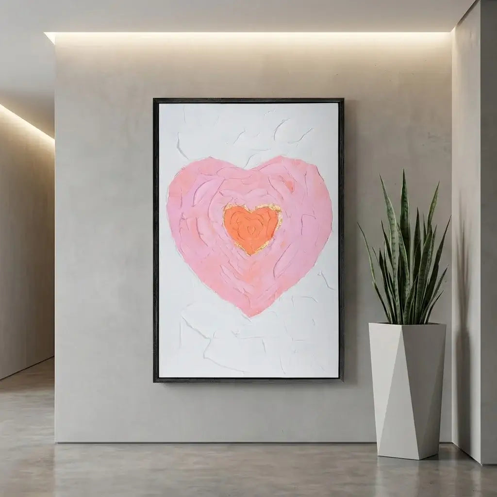 Framed abstract artwork of a pink heart with a plant on a neutral wall.