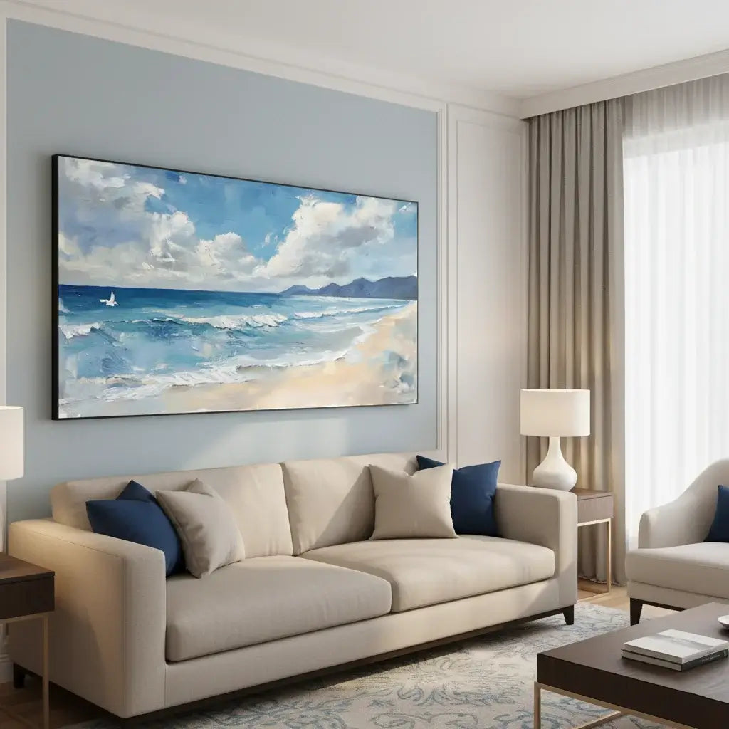 Modern living room with a beige sofa, blue pillows, and a large beach scene painting on the wall.