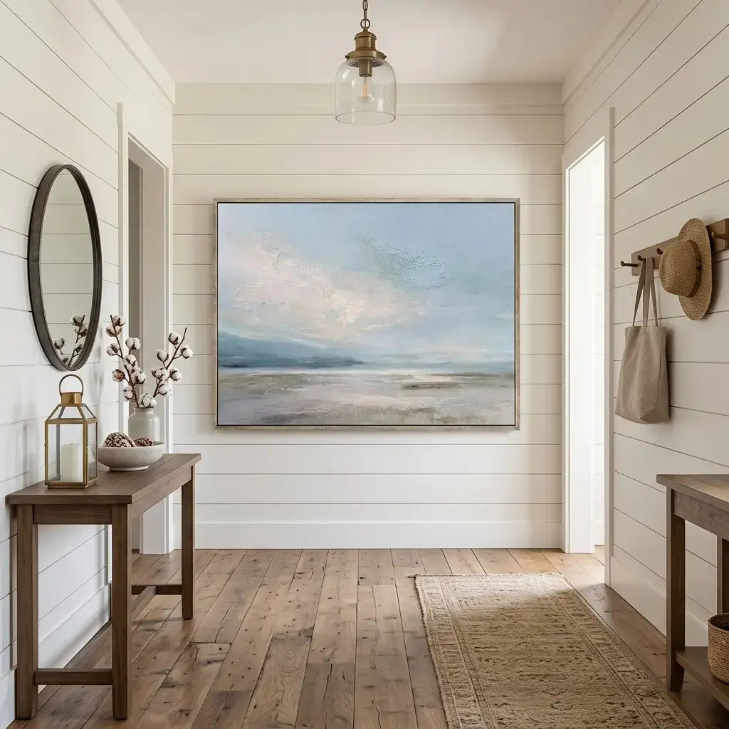 Nautical-themed room with a painting of a beach scene, lantern, and hat on a wall.